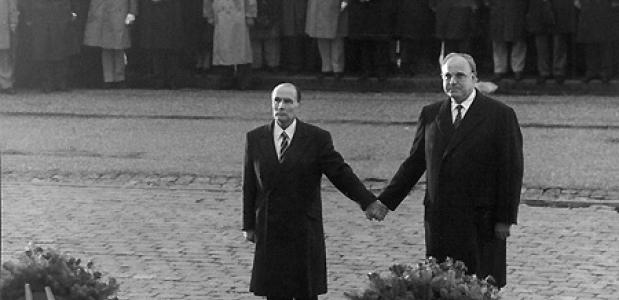 Mitterrand en Kohl houden elkaars hand vast tijdens de herdenking in Verdun, 1984. Bron: Maitresinh, Flickr.