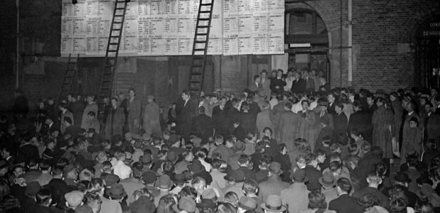 De uitslagen van de eerste naoorlogse verkiezingen worden groot getoond op de gevel van de Beurs van Berlage aan het Damrak.
