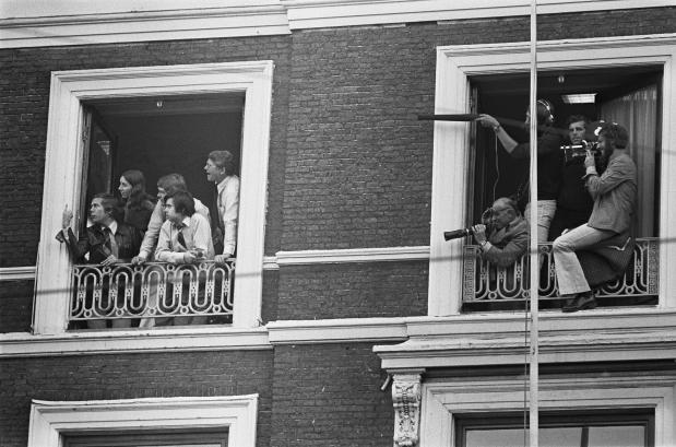 Journalisten hangen uit ramen in de buurt van de Franse ambassade tijdens de Haagse gijzeling