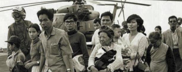Vietnamese vluchtelingen worden uit een helikopter geleid op een Amerikaans vliegdekschip.